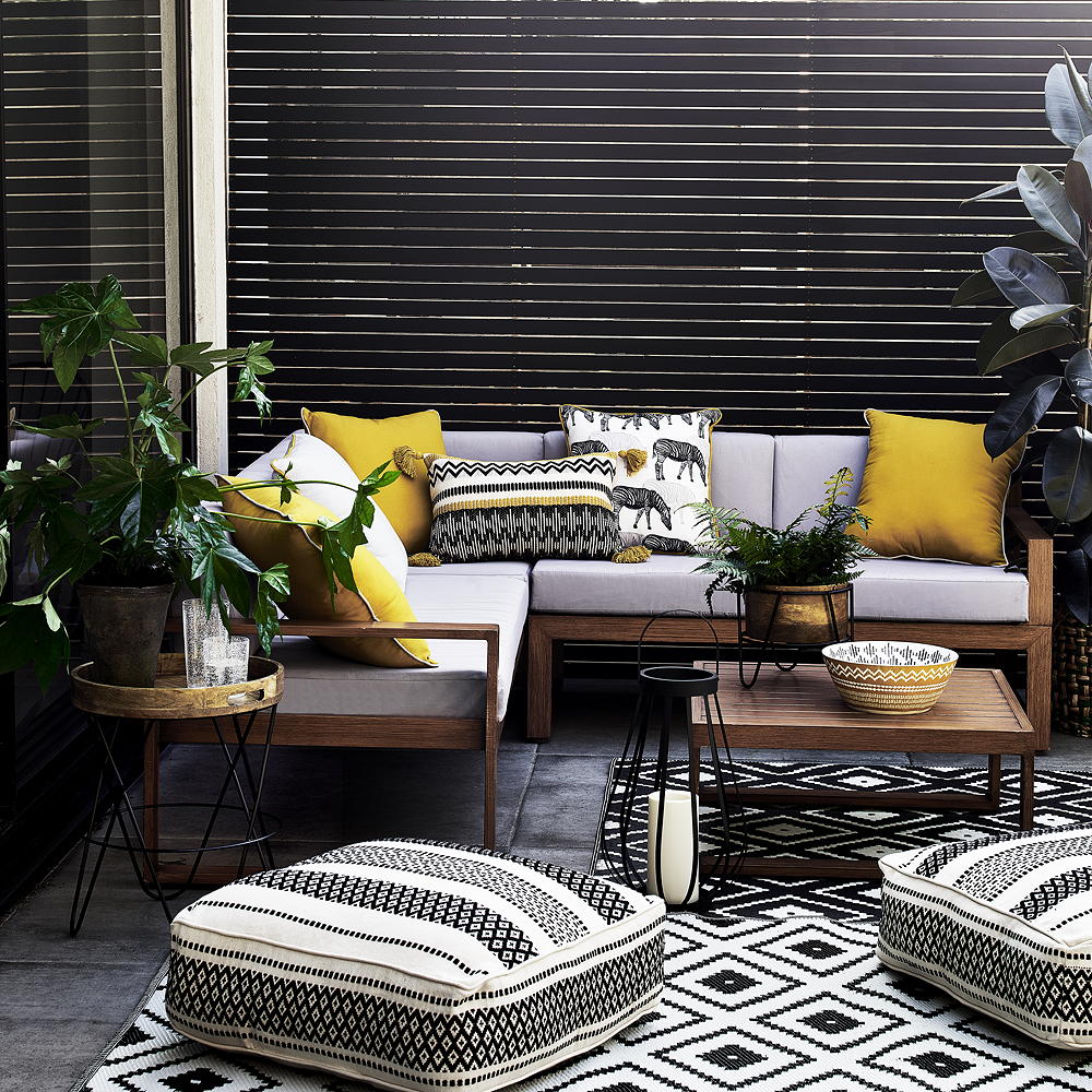Monochrome outdoor living room with sofa, coffee table, pouffes and rug