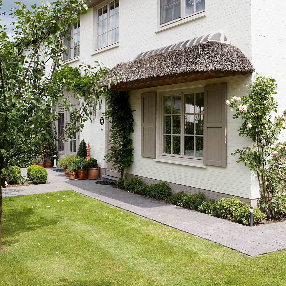 Exterior of house with thatched detailing and neat lawn