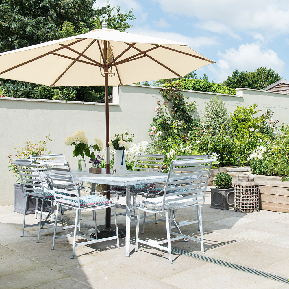 Metal table and chairs under cream umbrella in patio area